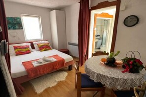 A bedroom with a bed, a bedside table with a vase, a chair, and a window. - Duga House Apartment  A4 (Crikvenica)
