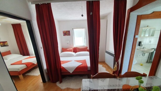 A bedroom with a bed, a mirror, and a bathroom visible through an open door.