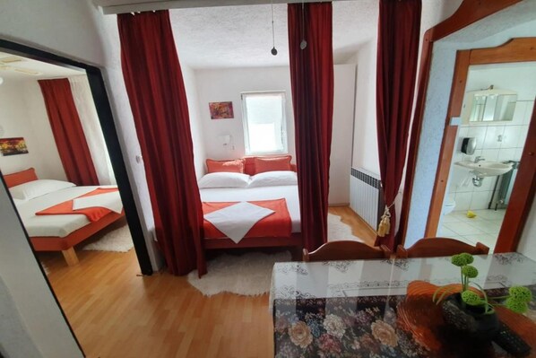 Een slaapkamer met een bed, een spiegel en een zichtbare badkamer door een geopende deur.