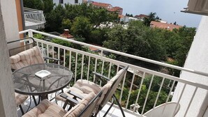 A balcony with a table and chairs, overlooking a body of water and buildings.