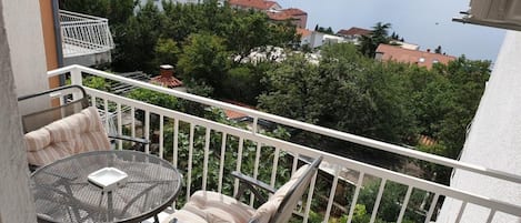 A balcony with a table and chairs, overlooking a body of water and buildings.
