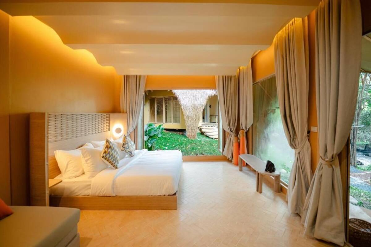 A spacious bedroom with a large bed, a bedside table, and a view of a garden.