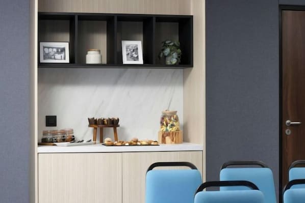 A modern room with a wooden cabinet, a white countertop, and two blue chairs. - Courtyard Paris Arcueil (Arcueil)