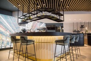 A modern bar area with a curved counter, bar stools, and a decorative shelf above. - Courtyard Paris Arcueil (Arcueil)