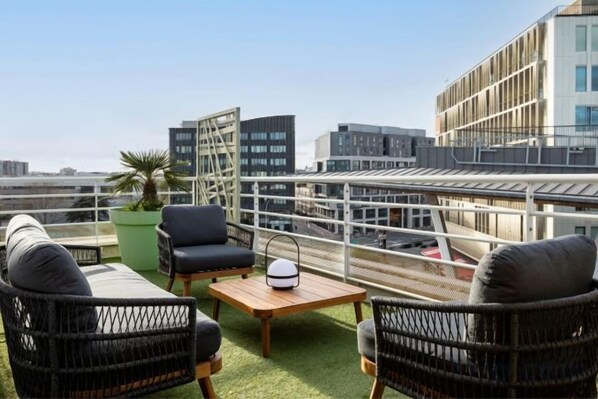 A rooftop terrace with outdoor seating, a potted plant, and a view of the cityscape. - Courtyard Paris Arcueil (Arcueil)