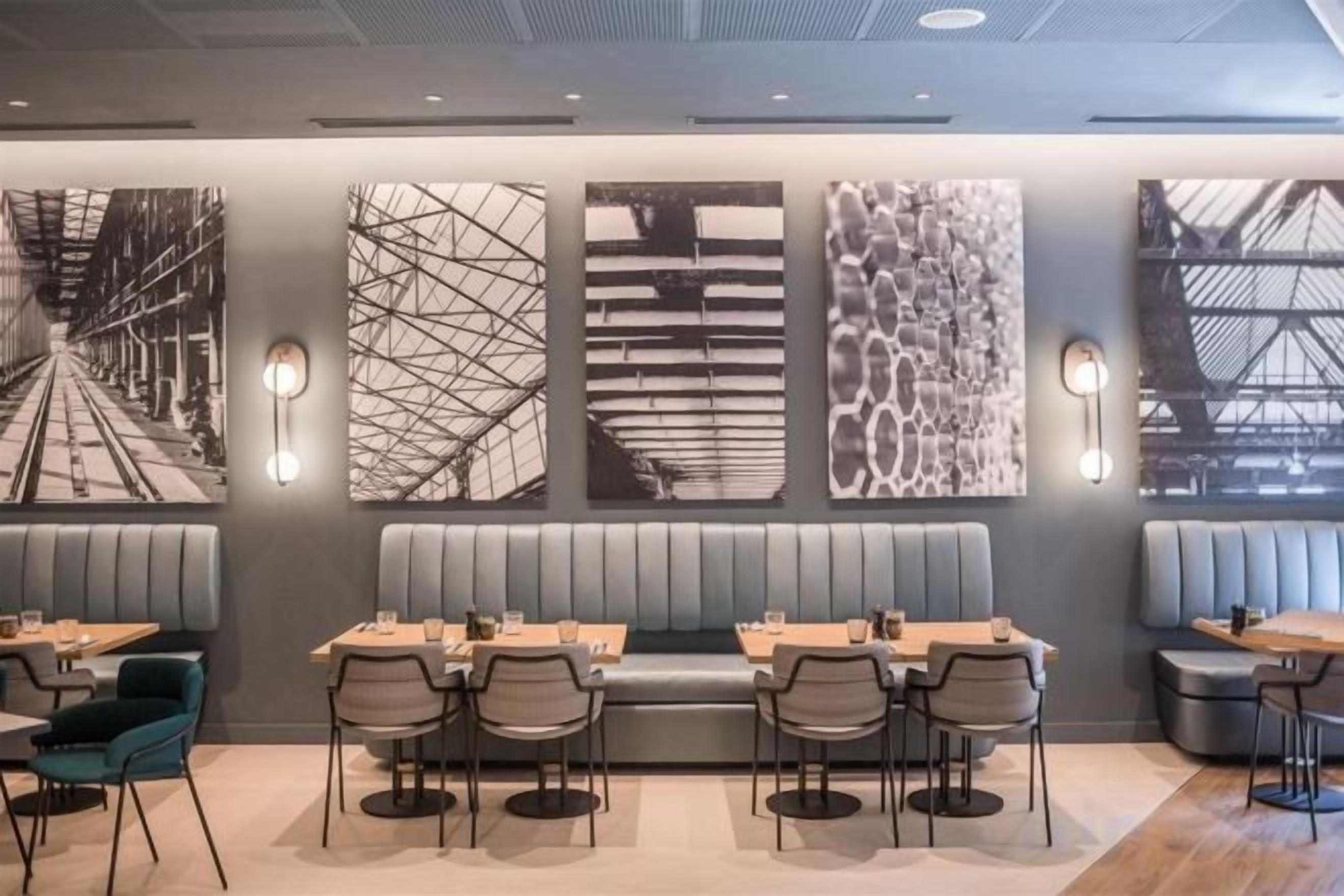 Un restaurant avec des banquettes et des tables, des œuvres d’art abstraites sur les murs et des luminaires suspendus.