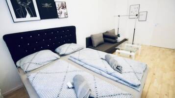Ein Zimmer mit zwei Betten, einem Schreibtisch und einem Stuhl. An der Wand befinden sich gerahmte Bilder.