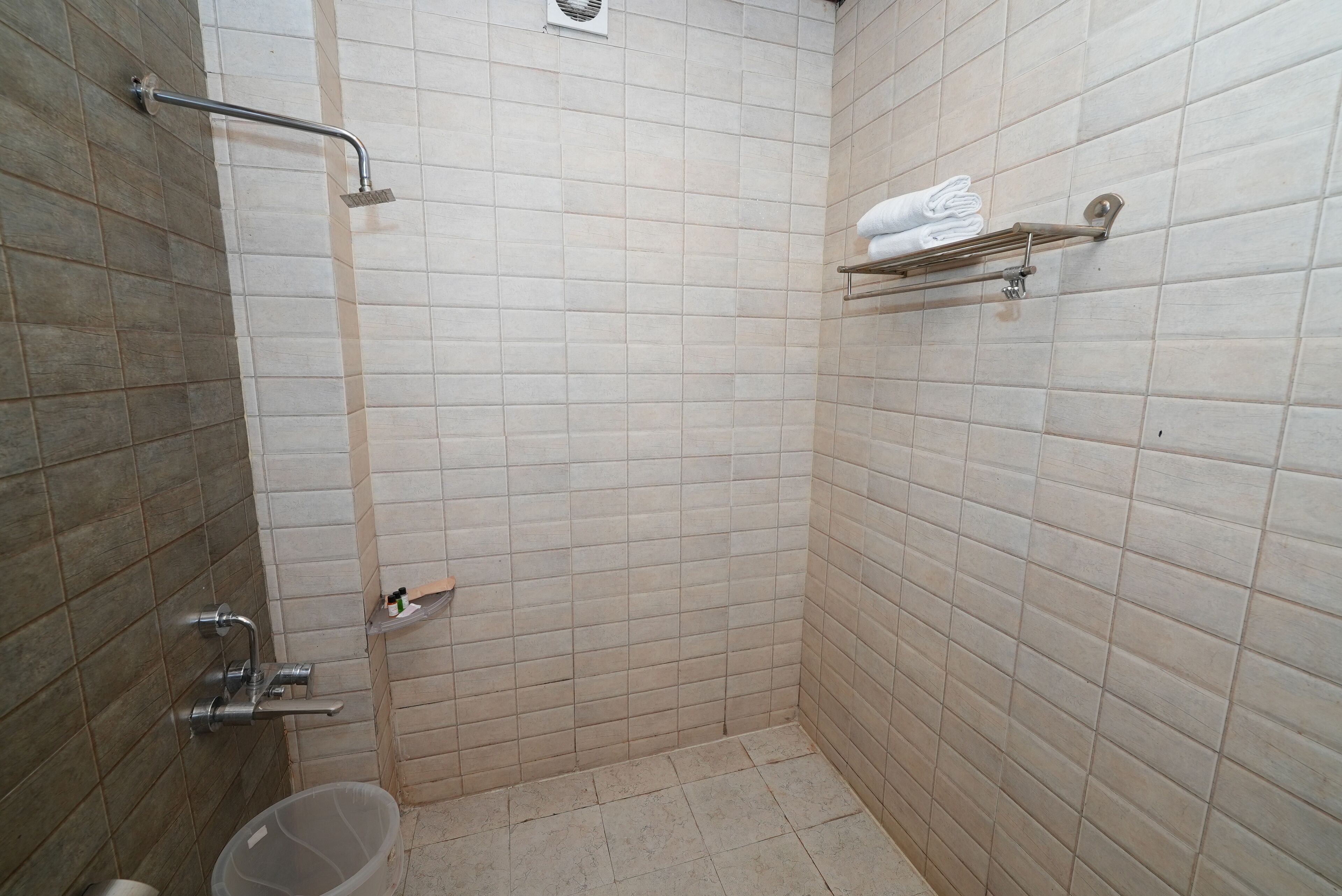 A small, tiled bathroom with a shower, a toilet, and a towel rack.