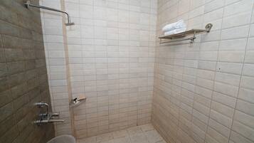 A small, tiled bathroom with a shower, a toilet, and a towel rack.