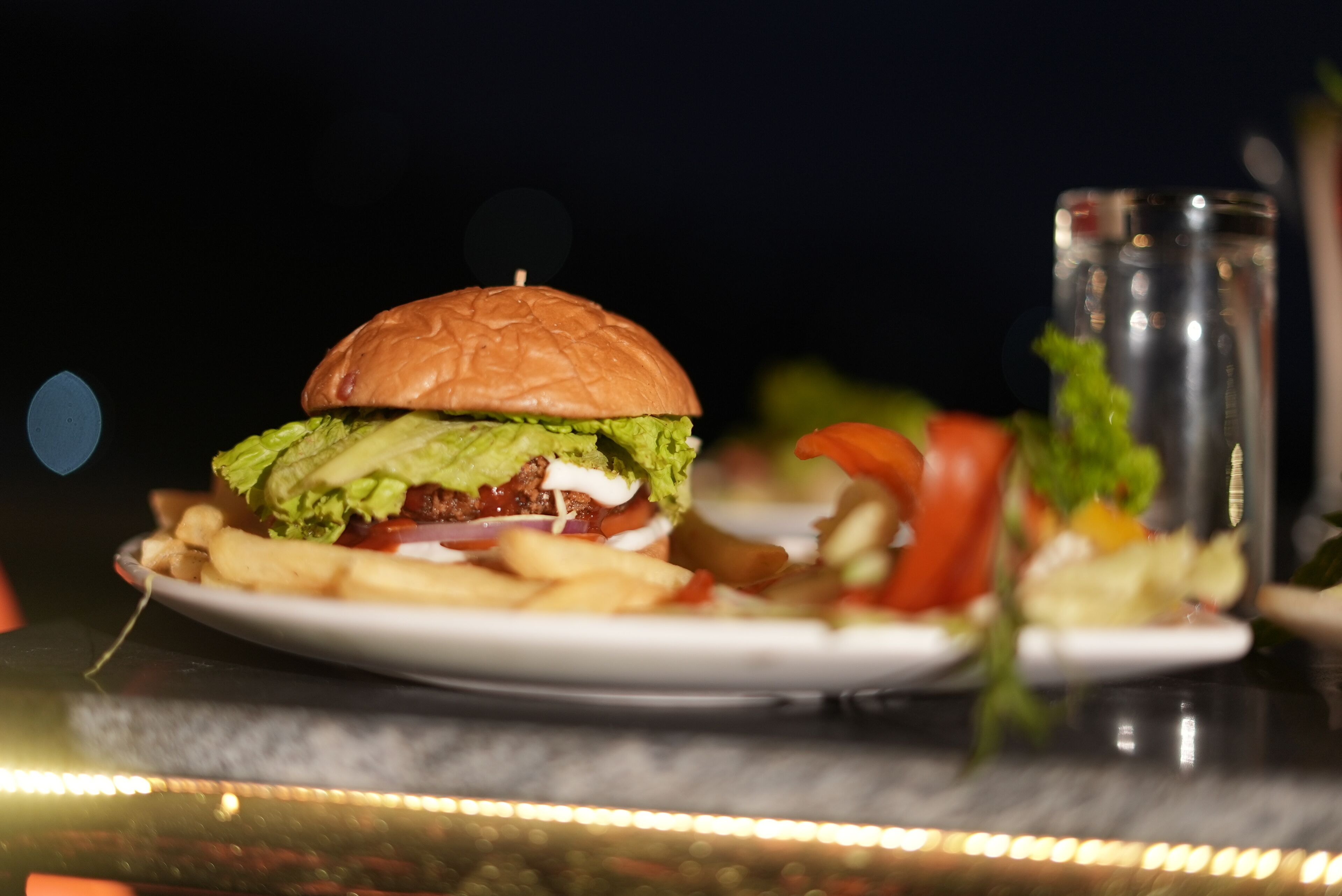 A burger with fries and a glass of water on a table.