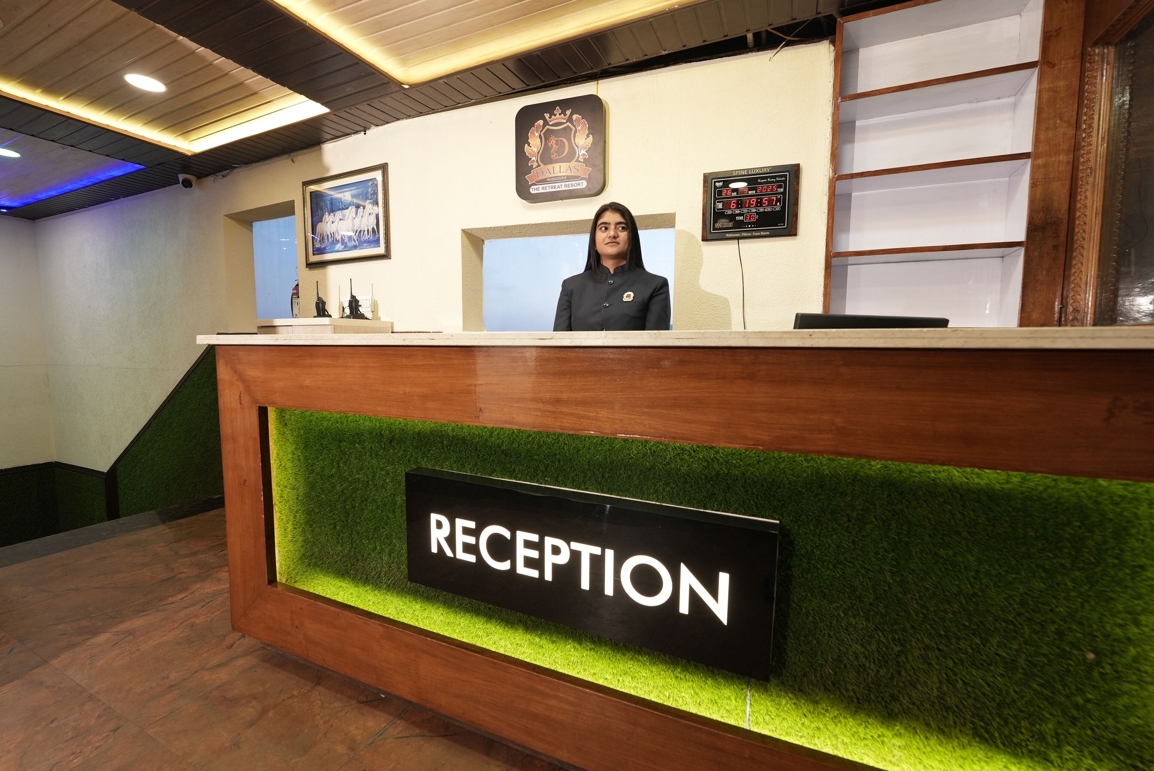 A reception desk with a 'RECEPTION' sign, a framed picture, and a digital display.