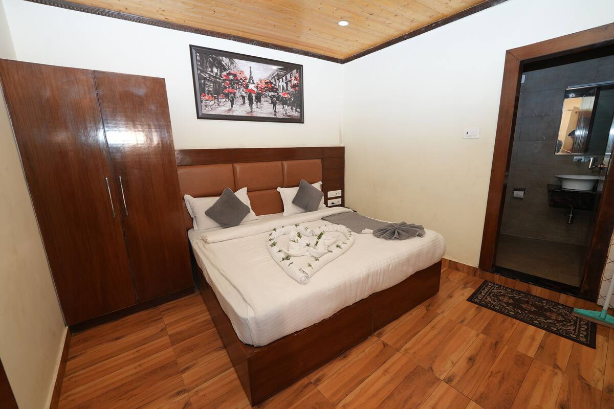 Ein Schlafzimmer mit einem hölzernen Bett, einem Kleiderschrank, einem Badezimmer mit Waschbecken und einem gerahmten Bild an der Wand.