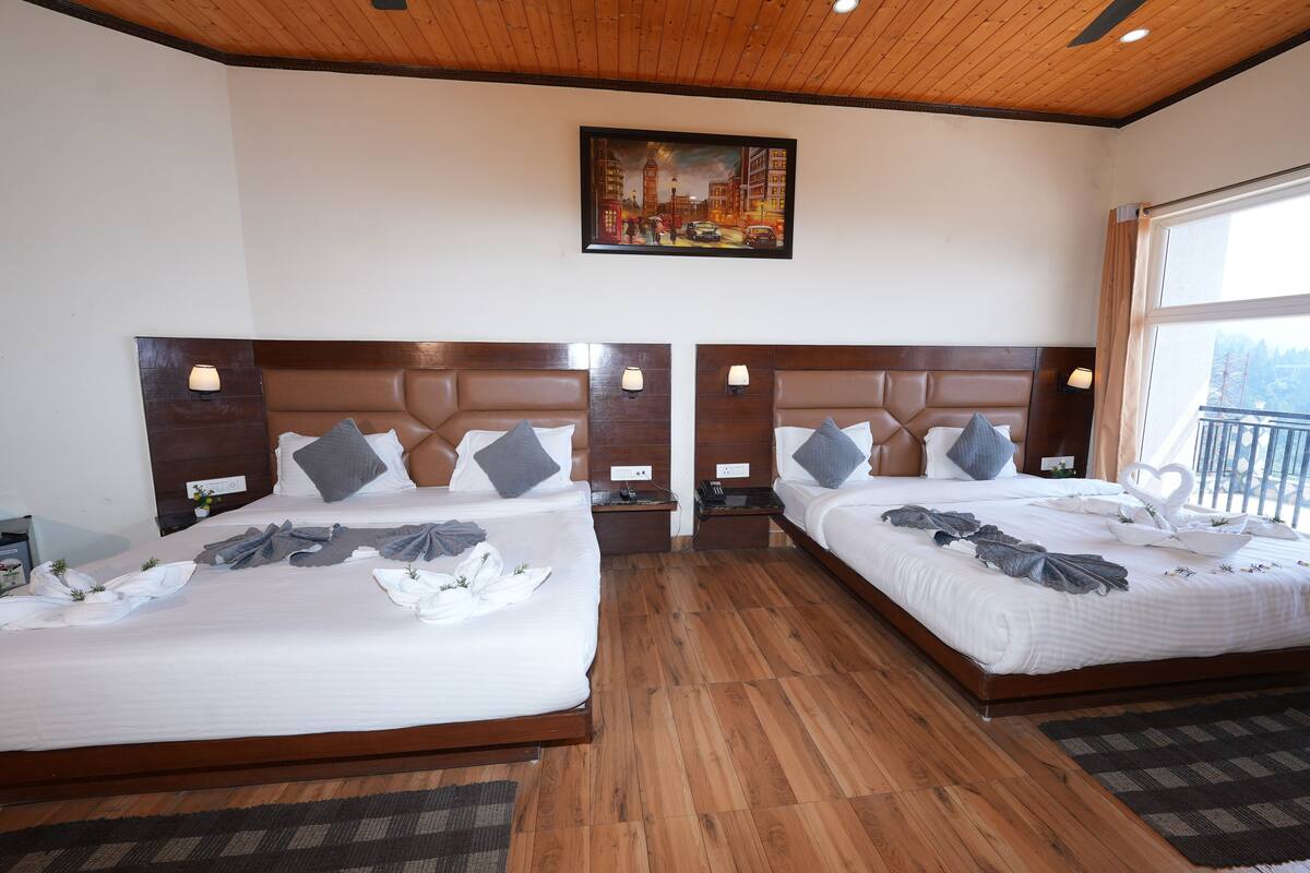 Ein Hotelzimmer mit zwei Betten, Holz-Kopfteilen, Nachttischlampen, einem Gemälde an der Wand und Blick ins Freie.