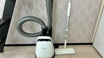 Aspiradora Toshiba con manguera y accesorio para fregar sobre un piso de madera.