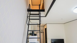 A narrow hallway with a black metal ladder leading to a loft area. A flat-screen TV is mounted on the wall in the loft. - Corpo SKR (Musashino)