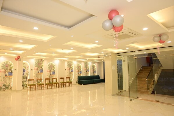 A spacious lobby with a green sofa, wooden chairs, and a staircase. - HOTEL ROYAL DIVINE (Varanasi)