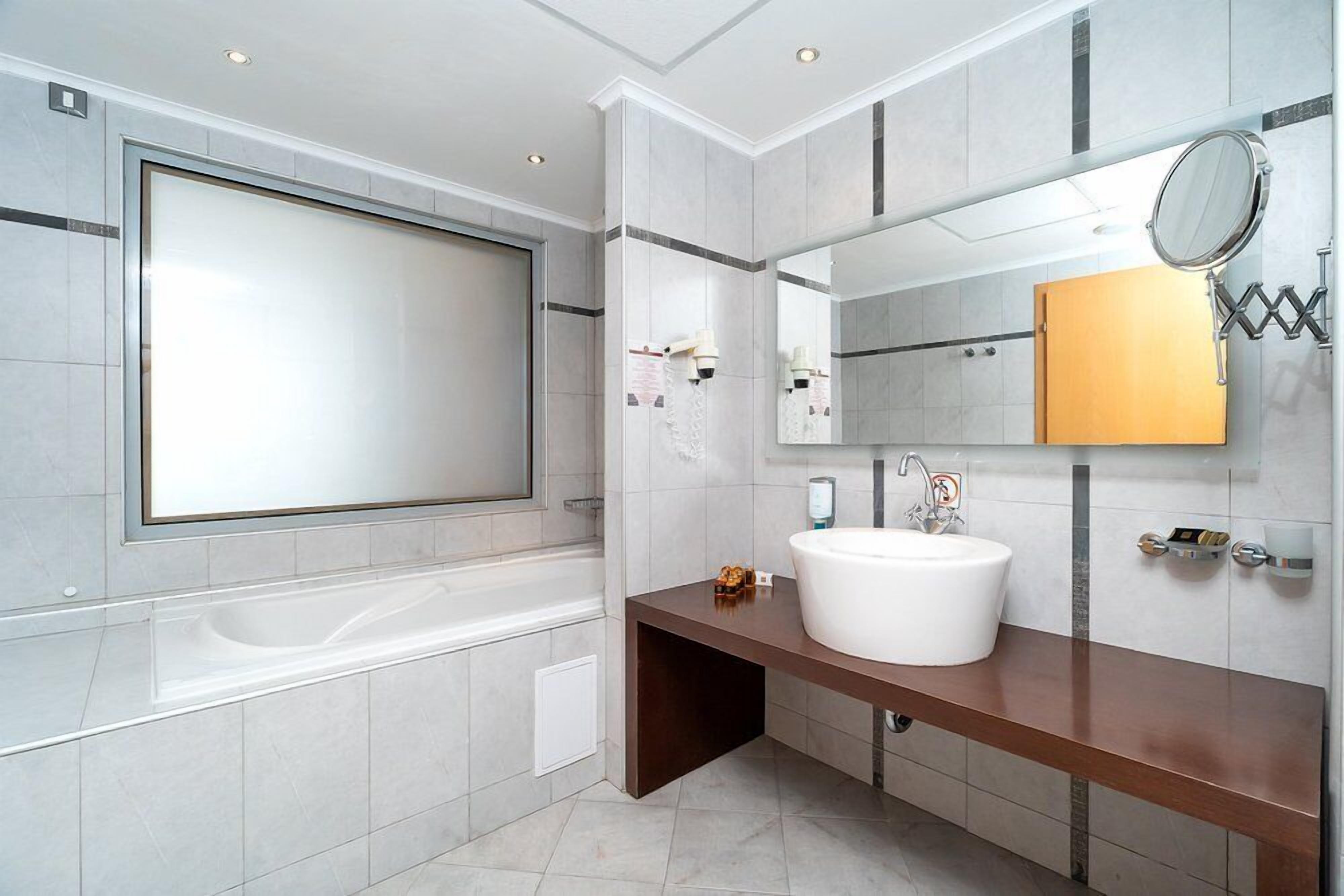 A modern bathroom with a large bathtub, a vanity with a sink, and a mirror.