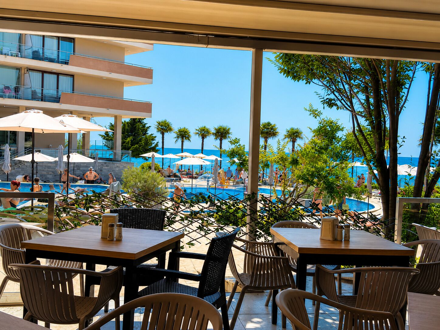 Ein Poolbereich mit Außenmöbeln und Blick auf Pool und Strand.