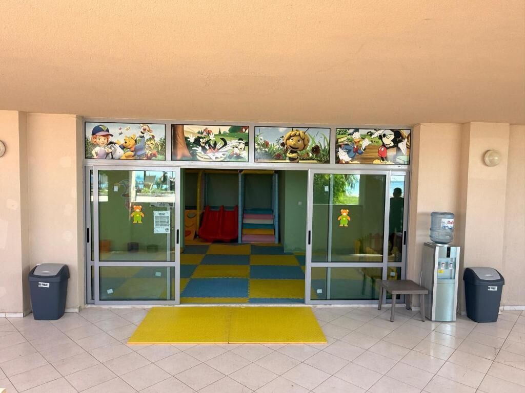 A children's play area with colorful mats, a water dispenser, and trash bins.