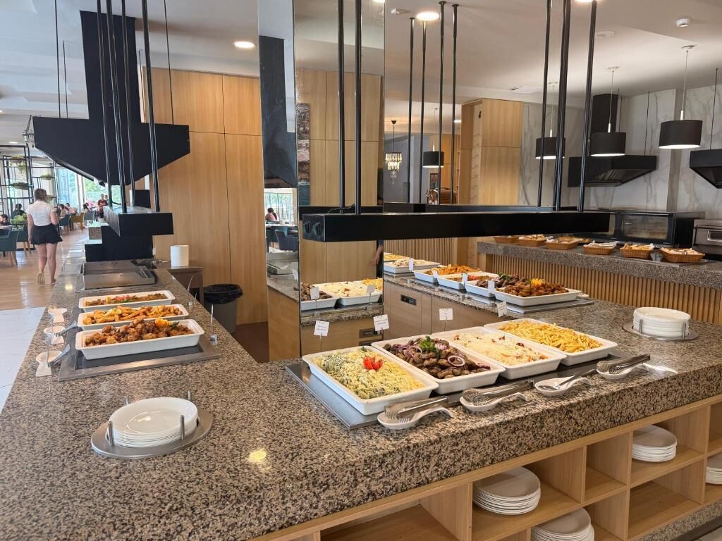 A buffet with various food options and a seating area with tables and chairs.