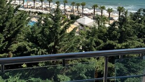 Une vue sur la plage, avec des palmiers, des parasols et une piscine.