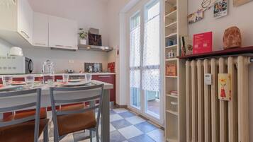 Una cocina moderna con armarios blancos, una mesa de comedor para dos personas y un radiador a la derecha.