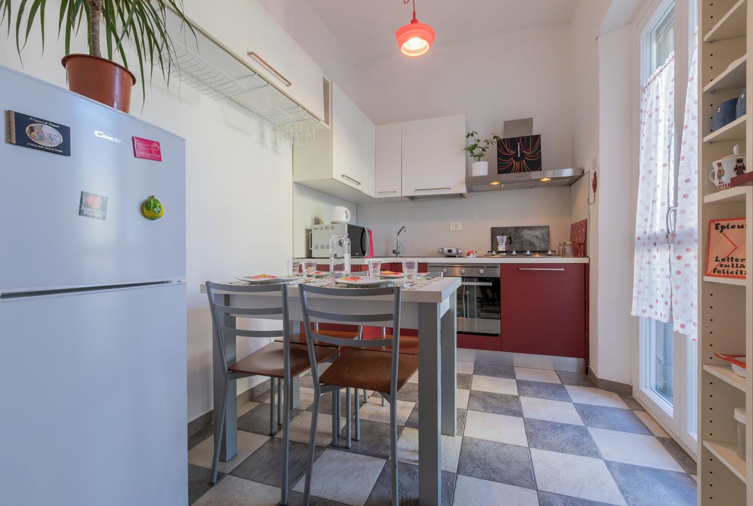 A compact kitchen with a dining area, featuring a refrigerator, microwave, oven, and a small island with a sink.