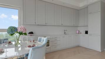 A modern kitchen with white cabinetry, a dining table set for four, and a vase with flowers.