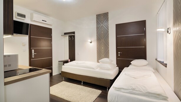 A modern hotel room with a kitchenette, two single beds, a large mirror, and a patterned wall. - Paulay Downtown Apartments (Budapest)