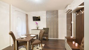 A modern room with a dining table, chairs, a TV, and a wardrobe. - Paulay Downtown Apartments (Budapest)
