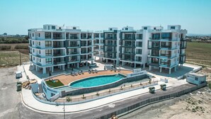 A modern multi-story residential building with a central swimming pool, balconies, and a landscaped area.