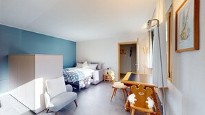 Een moderne slaapkamer met een bed, een bureau, een stoel en een kledingkast.
