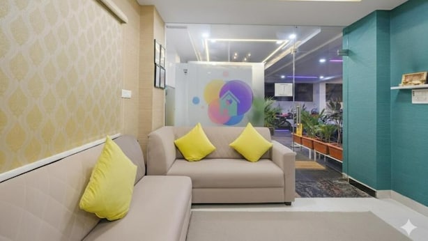 Un hall moderno con un sofá y cojines, un logotipo colorido en la pared y un mostrador de recepción.