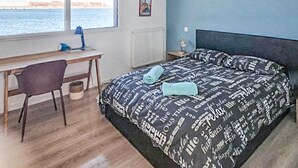 A bedroom with a bed, a desk, and a chair. There is a window with a view of the sea. - Beautiful apartment in Dunkerque with WiFi (Dunkerque)