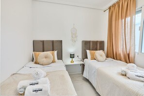 Una habitació d'hotel amb dos llits, una taula de nit amb una làmpada i un penjador de somnis a la paret.