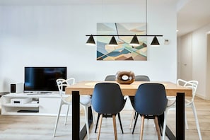 A modern dining area with a wooden table, black chairs, and a flat-screen TV. - Conquistador C (El Campello)