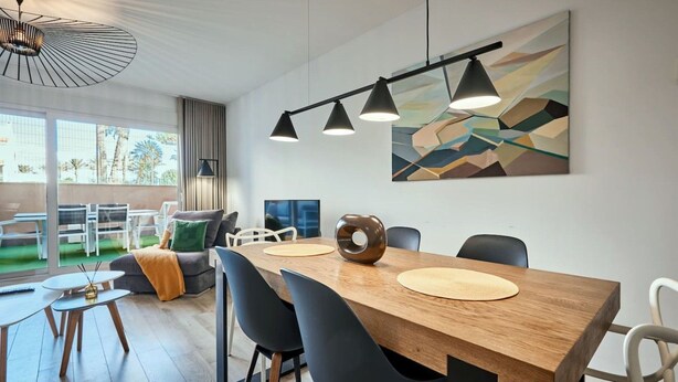 A modern dining area with a wooden table, black chairs, and pendant lighting. - Conquistador C (El Campello)