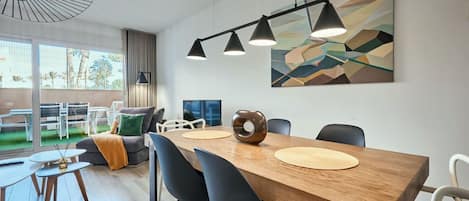 A modern dining area with a wooden table, black chairs, and pendant lighting.