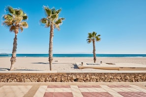 Una playa con palmeras y un muro de piedra.