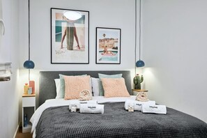 A modern hotel room with a bed, pillows, a bedside table with a lamp, and framed pictures on the wall. - Conquistador C (El Campello)