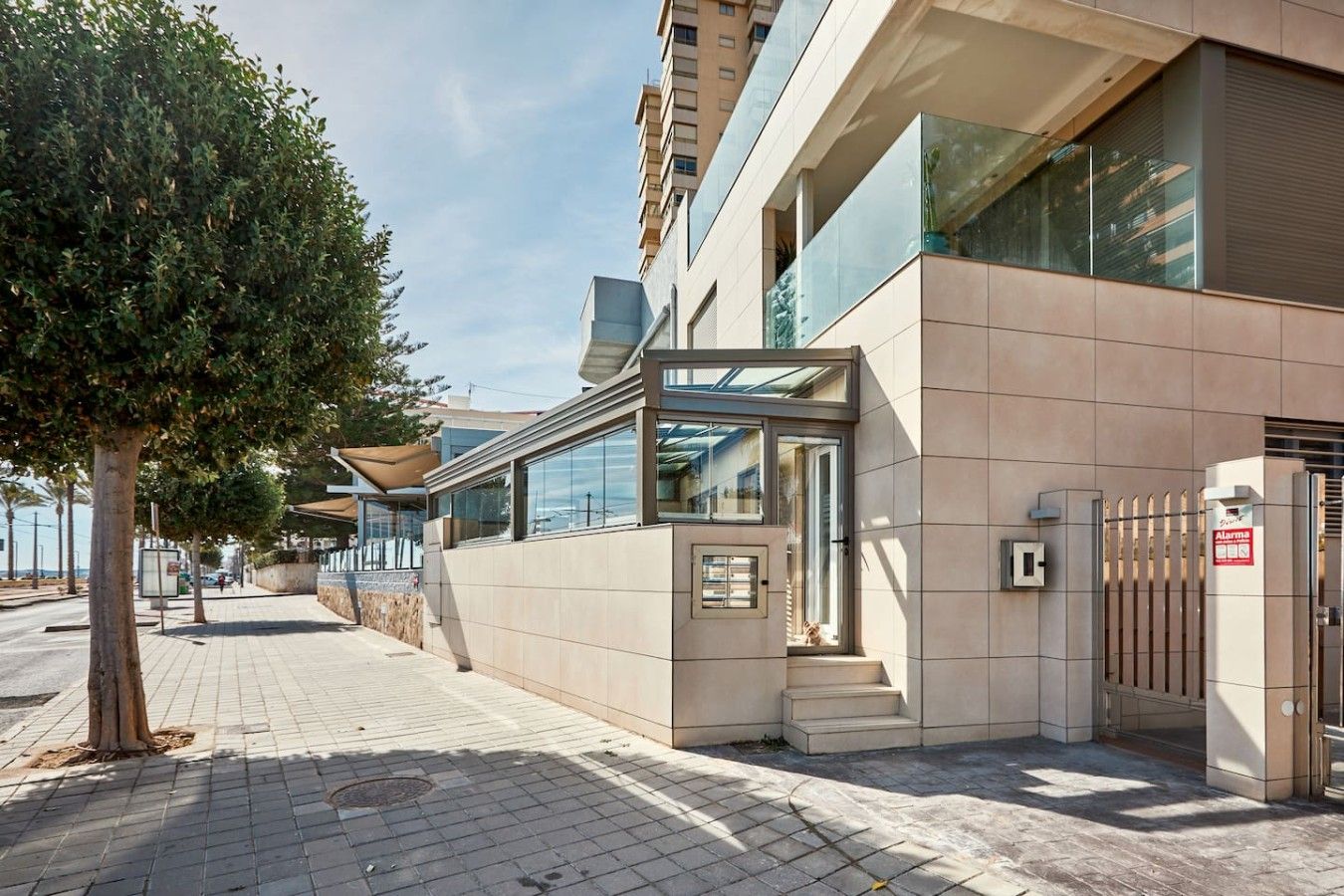 A modern building with a glass entrance, a visible staircase, and a gated area.