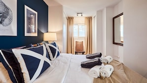 Une chambre d’hôtel avec un lit, une chaise, une lampe et une fenêtre avec des rideaux.
