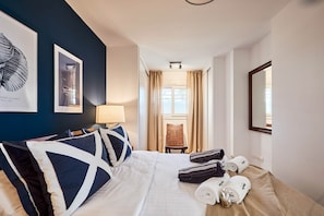Una habitación de hotel con una cama, una silla, una lámpara y una ventana con cortinas.