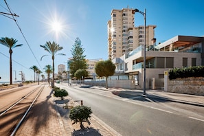 Una calle urbana moderna con tranvía, palmeras y edificios contemporáneos.
