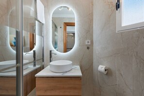 A modern bathroom with a round mirror, a white sink, and a glass shower enclosure. - San Pedro de Pinatar (San Pedro del Pinatar)