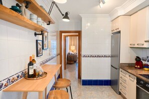 A compact kitchen with a wooden countertop, a built-in oven, and a refrigerator. There is a dining area with a wooden table and chairs. - San Pedro de Pinatar (San Pedro del Pinatar)