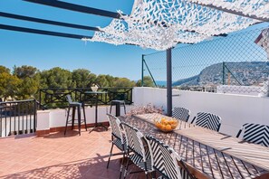 Une terrasse avec une table et des chaises, un parasol décoratif et une vue sur le paysage.