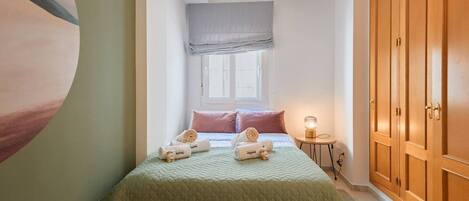 A bedroom with a bed, pillows, a bedside lamp, and a wardrobe.