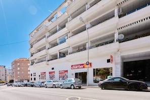 A multi-story building with a charter store on the ground floor, multiple balconies, and parked cars.