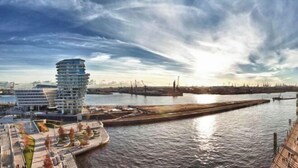 A waterfront hotel with a modern design, a river, and a view of the city skyline.